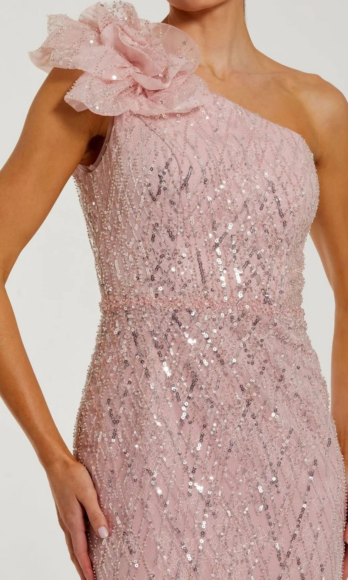 A woman wearing the Mac Duggal 21199 long formal dressโa stunning pink, one-shoulder gown adorned with sequins and a large floral embellishment on the shoulder, exuding elegant style.